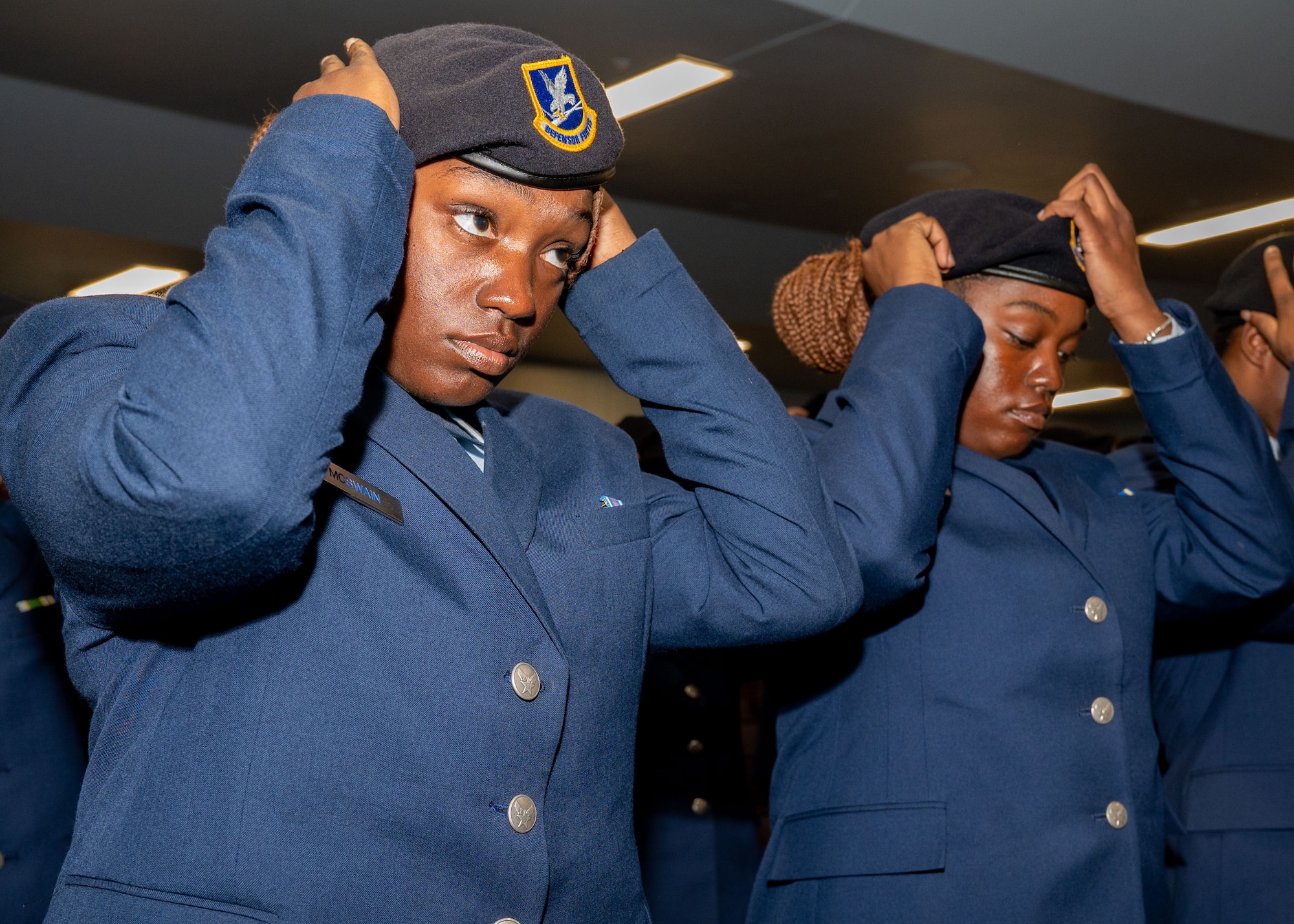 Defenders adjust berets during the Basic Defender Course Graduation at Joint Base San Antonio-Lackland, Texas, Feb. 6, 2024. The 343rd Training Squadron is optimizing training to ensure Defenders are equipped with the skills and knowledge needed to tackle evolving threats in a modern era. The 343 TRS Security Forces technical training is one of the key components in the Defender Next initiative, where the career field is undertaking the largest shift in the schoolhouse in over two decades.  (U.S. Air Force photo by Vanessa R. Adame)