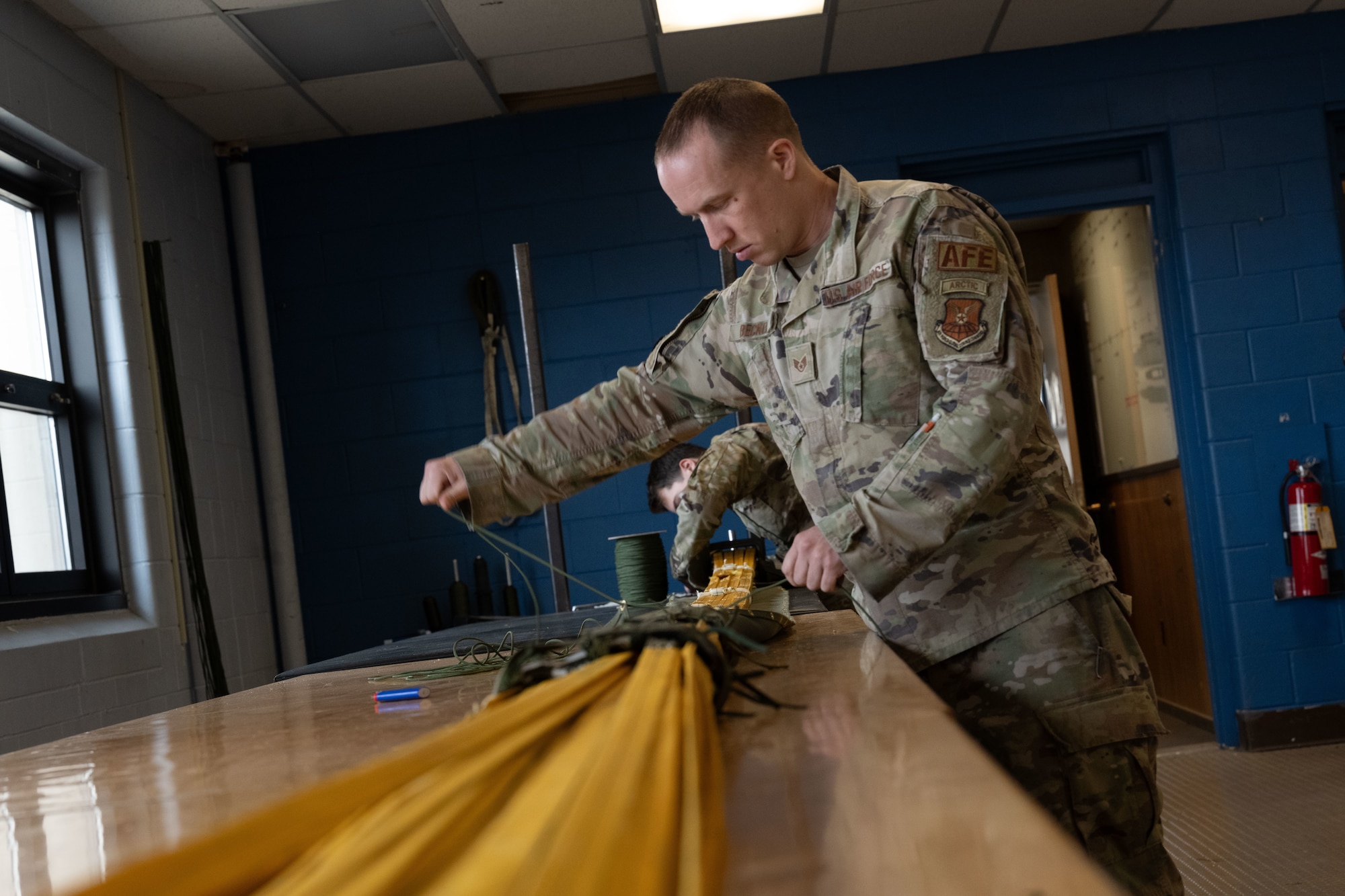 U.S. Air Force Staff Sgt. Jeremy Becker, 5th Operations Support Squadron aircrew flight equipment non-commissioned officer in charge, prepares a parachute for inspection during Prairie Vigilance 24-3 at Minot Air Force Base, North Dakota, April 8, 2024. These exercises enable crews to maintain a high state of readiness and proficiency, while validating the always-ready, global strike capability. (U.S. Air Force photo by Airman 1st Class Trust Tate)