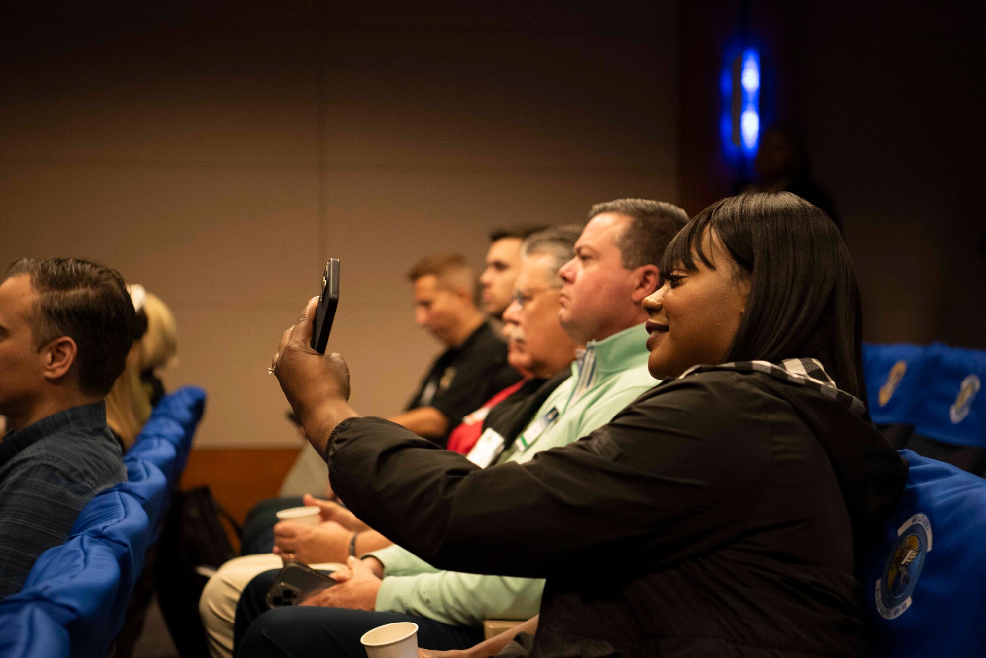 A person takes a photo on a camera phone during a brief.