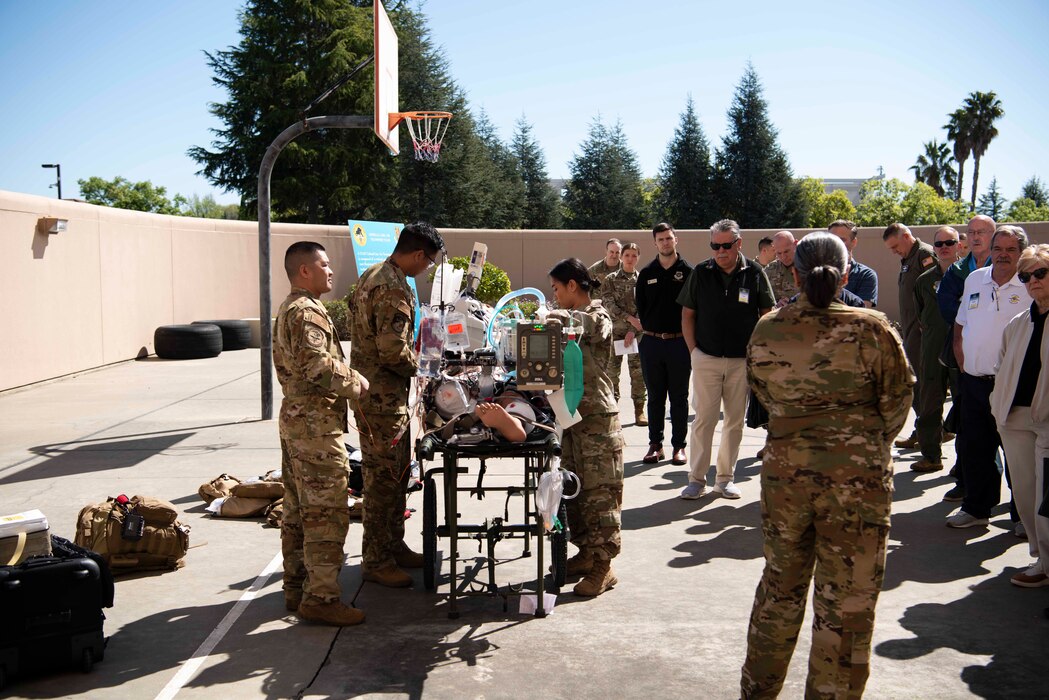 Airmen demonstrate medical procedures on a mannequin in front of a large group of people