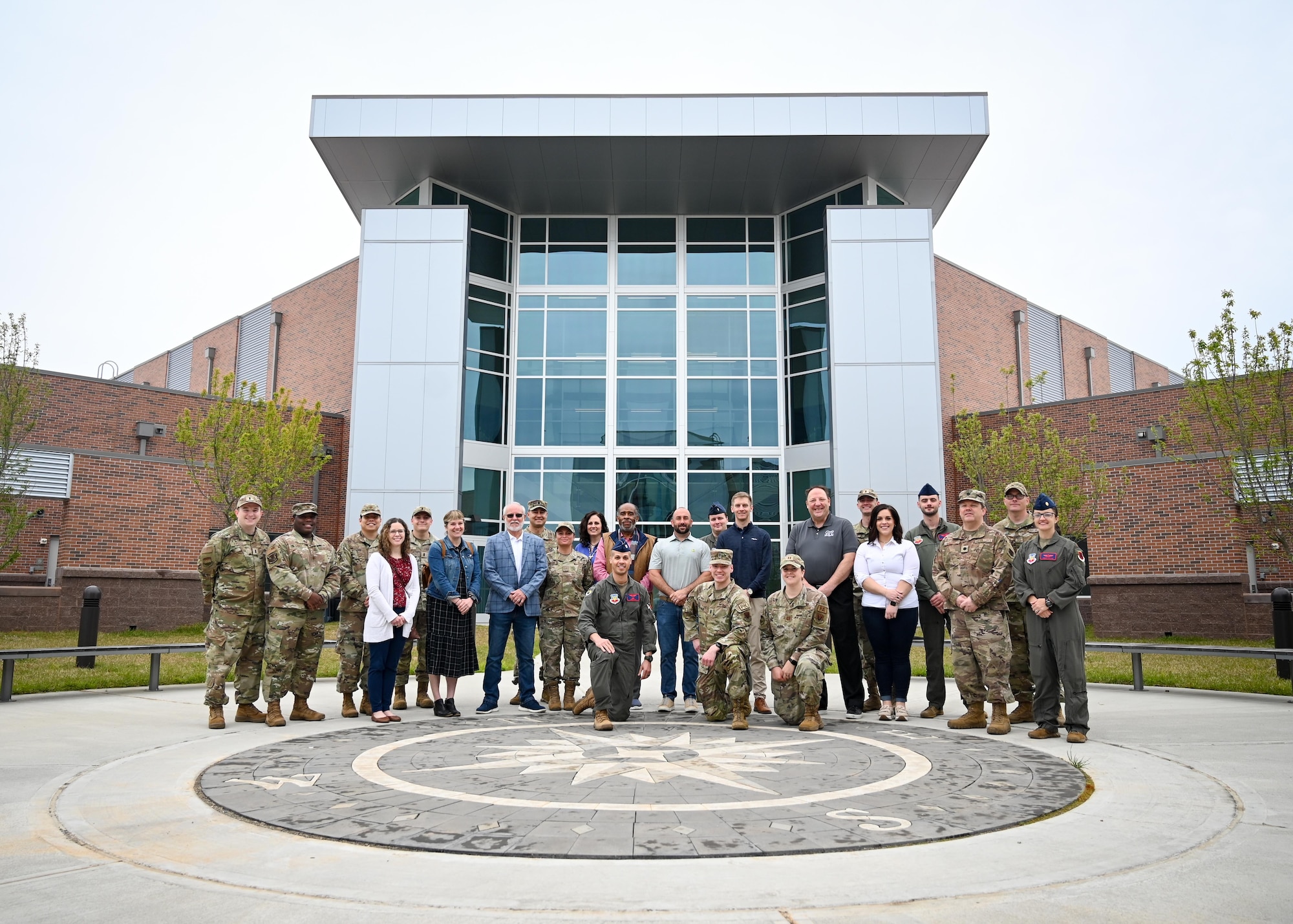 Civilians and military personnel pose for a group photo.