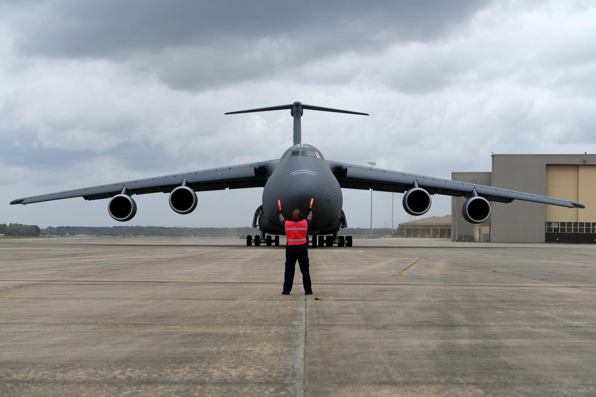 Greg McLean, a transient aircraft service contractor with C2G Limited, marshals a U.S. Air Force C-5M Super Galaxy assigned to the 337th Airlift Squadron from Westover Air Reserve Base, Mass., on the flightline at Shaw Air Force Base, S.C., March 22, 2024. The C-5M landed at Shaw AFB prior to a joint forcible entry exercise in which they would be transporting two U.S. Army AH-64E Apache Guardian helicopters to the training area in Florida. (U.S. Air Force photo by Staff Sgt. Kelsey Owen)