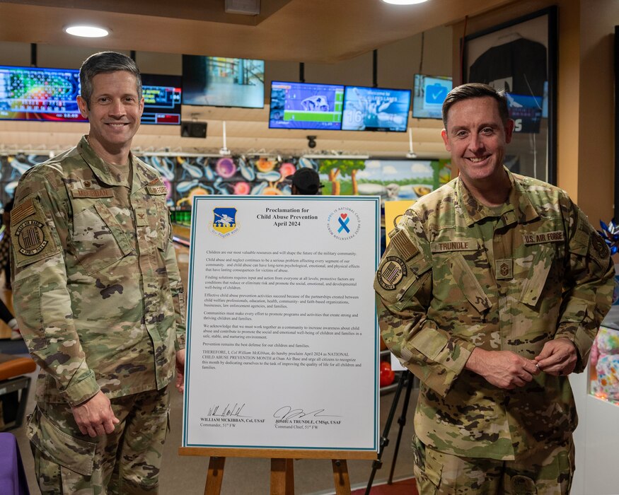 U.S. Air Force Col. William McKibban, 51st Fighter Wing commander, left, and Chief Master Sgt. Joshua Trundle, 51st FW command chief, pose next to the Proclamation for Child Abuse Prevention Month after signing it at Osan Air Base, Republic of Korea, April 5, 2024. McKibban and Trundle designated April as National Child Abuse Prevention Month for Osan AB. (U.S. Air Force photo by Staff Sgt. Aubree Owens)