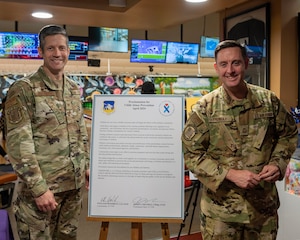 U.S. Air Force Col. William McKibban, 51st Fighter Wing commander, left, and Chief Master Sgt. Joshua Trundle, 51st FW command chief, pose next to the Proclamation for Child Abuse Prevention Month after signing it at Osan Air Base, Republic of Korea, April 5, 2024. McKibban and Trundle designated April as National Child Abuse Prevention Month for Osan AB. (U.S. Air Force photo by Staff Sgt. Aubree Owens)