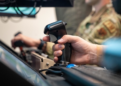 An Airman operates the steering handle of a flight simulator.