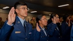 Security Forces technical training students raise their hands as they recite the Security Forces pledge during the Basic Defender Course graduation at Joint Base San Antonio-Lackland, Texas, Jan. 16, 2024. The 343rd Training Squadron is optimizing training to ensure Defenders are equipped with the skills and knowledge needed to tackle evolving threats in a modern era. The 343 TRS Security Forces technical training is one of the key components in the Defender Next initiative, where the career field is undertaking the largest shift in the schoolhouse in over two decades.  (U.S. Air Force photo by Vanessa R. Adame)
