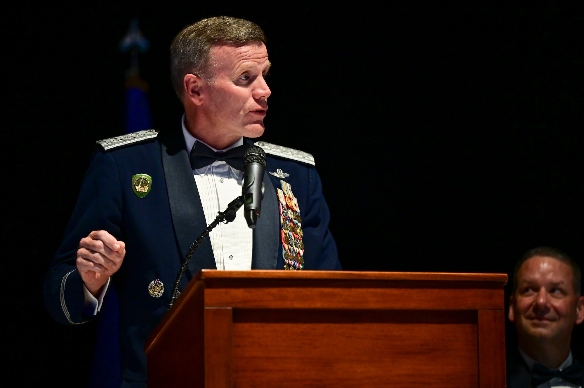 A uniformed man gesticulates while standing at a podium.