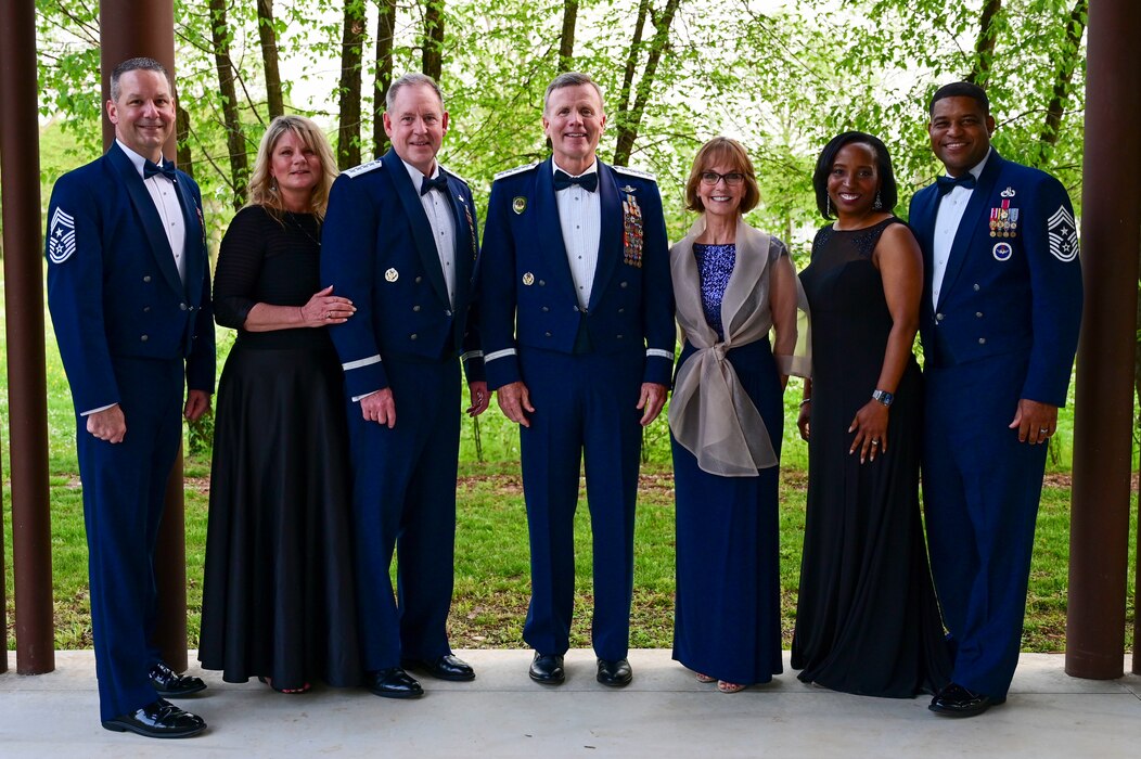 a group of military members and their spouses stand facing the camera