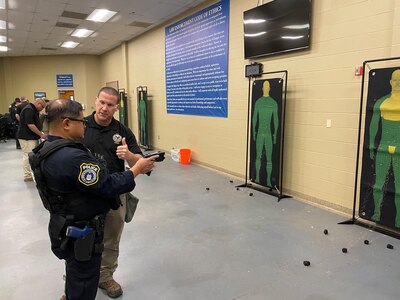 trainer instructs student near non-lethal weapons targets