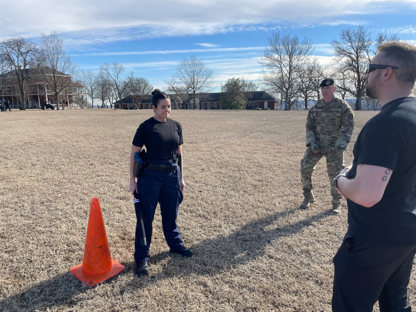 student holds baton in an outside training scenario while instructor talks to them.