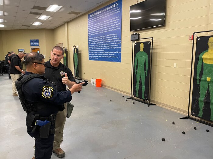 trainer instructs student near non-lethal weapons targets