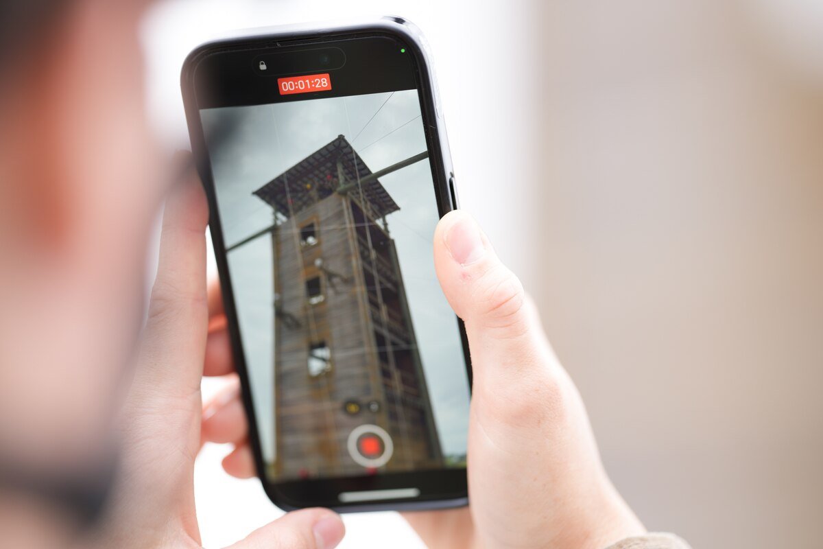 U.S. Air Force Officer Training School trainee records video of another trainee as they rappel down a wall during their module three Blue Thunder obstacle course training, at Maxwell Air Force Base, Alabama. The obstacles prepare trainees for future combat employment operations and encourage team-building.
