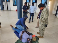 U.S. Navy Hospital Corpsman 1st Class Marcos Ramirez, assigned to Naval Mobile Construction Battalion (NMCB) 11 teaches fisheries inspectors how to apply a torniquet during first-aid training at the Ghana Naval Training Command (NAVTRAC) in Nutekpor-Sogakope in the Volta Region of Ghana, Feb. 26, 2024. The training was held as part of a Visit, Board, Search and Seizure (VBSS) course led by the United Nations Office of Drugs and Crime (UNODC) Global Maritime Crime Programme (GMCP). NMCB 11, assigned to the TWENTY SECOND Naval Construction Regiment, is forward deployed across the U.S. Naval Forces Europe-Africa area of operations, in support of U.S. Sixth Fleet maritime operations to defend U.S., allied, and partner interests. (Courtesy Photo)