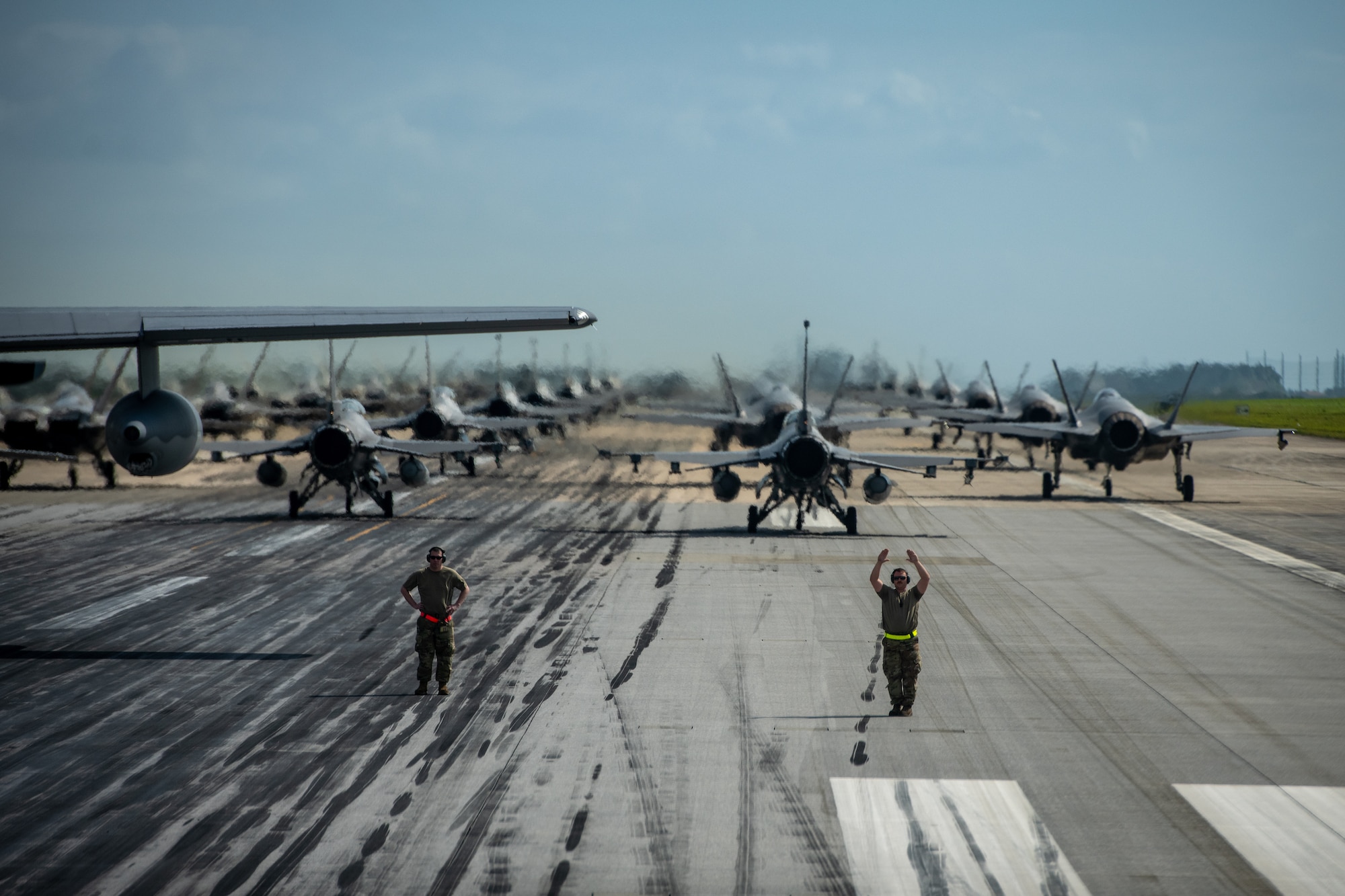 Airmen marshal aircraft into formation on a runway