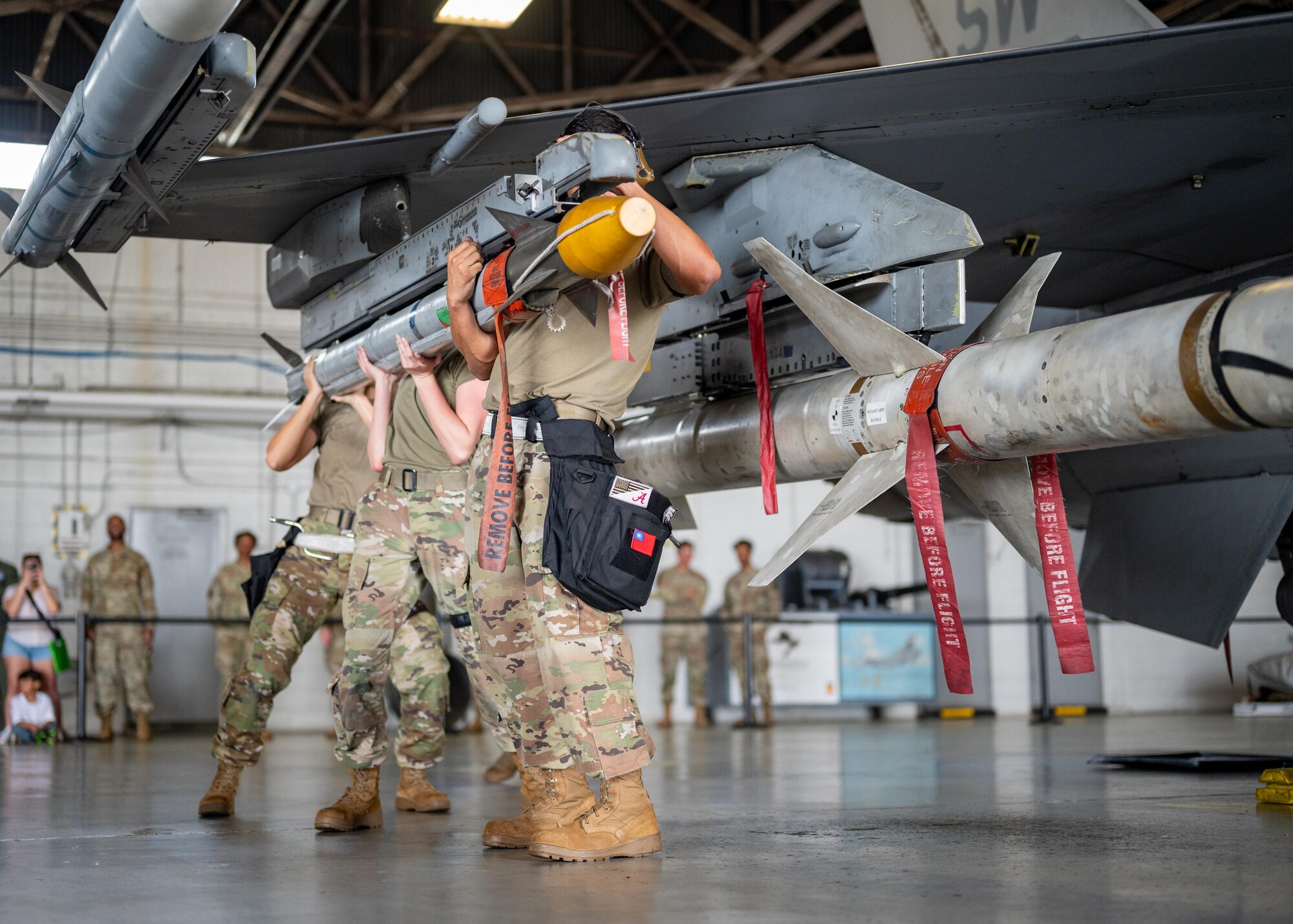 A load crew works together to lift a munition onto an aircraft.