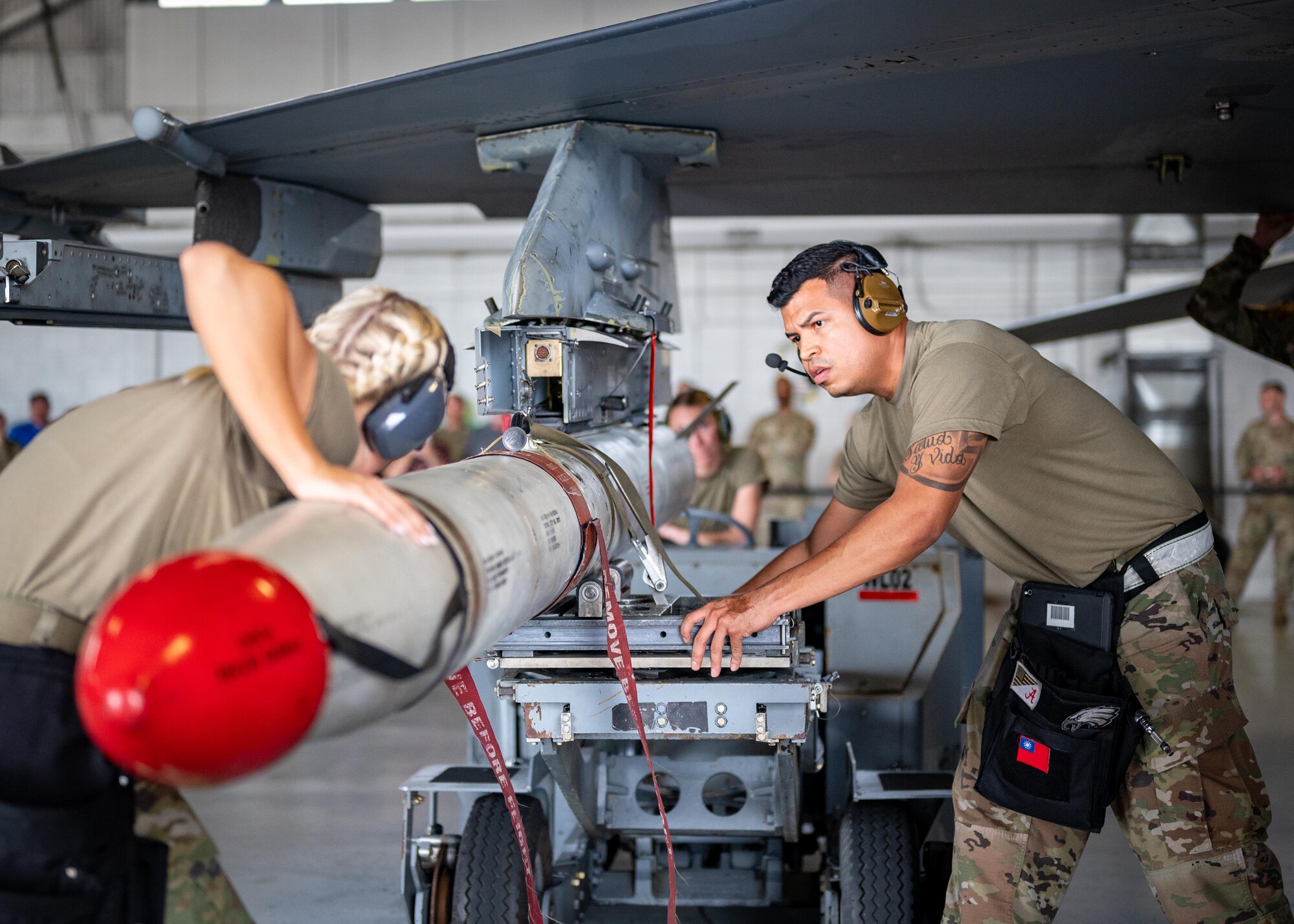 A load crew works to mount a munition onto an aircraft.