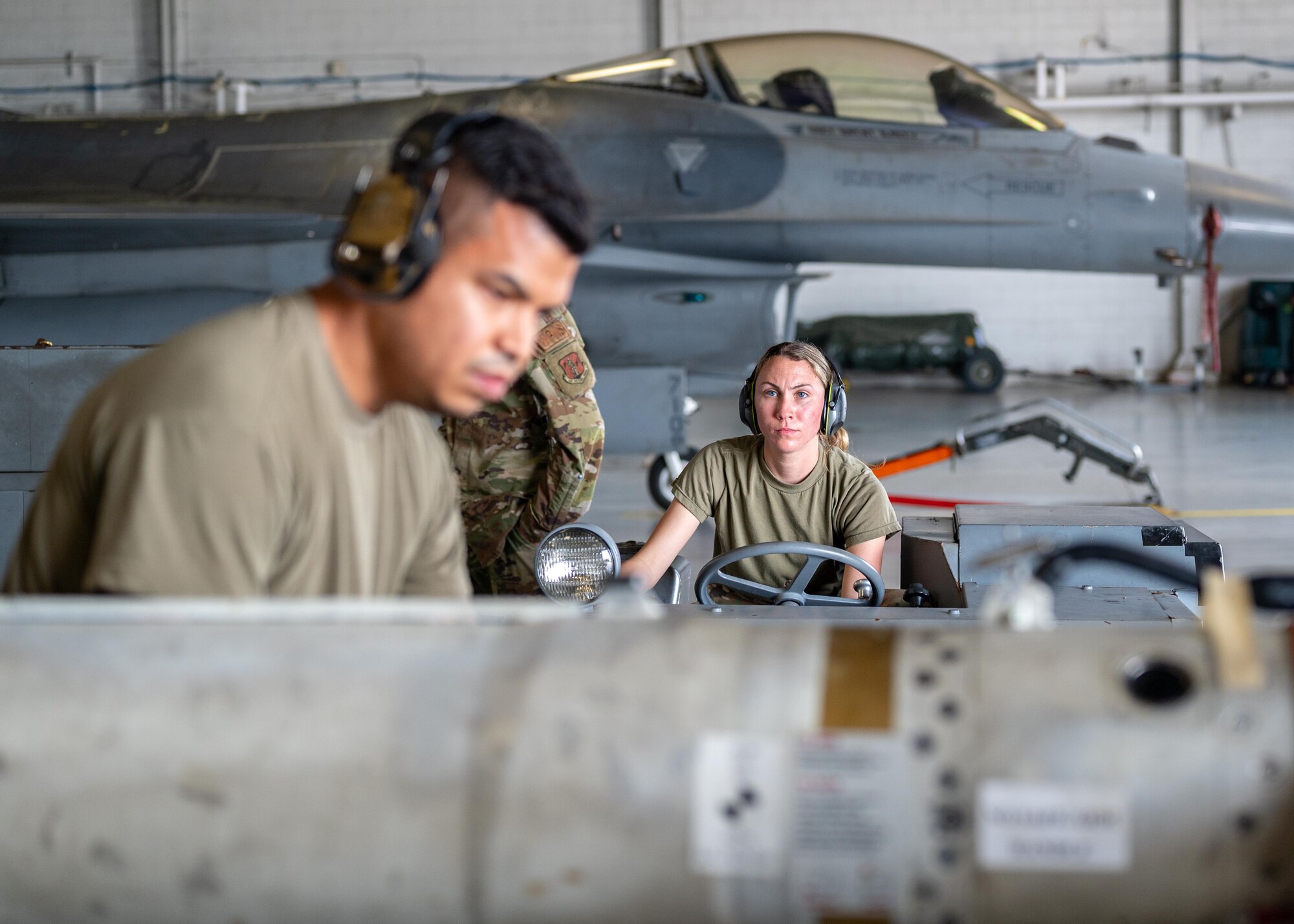A load team works together to lift a munition.