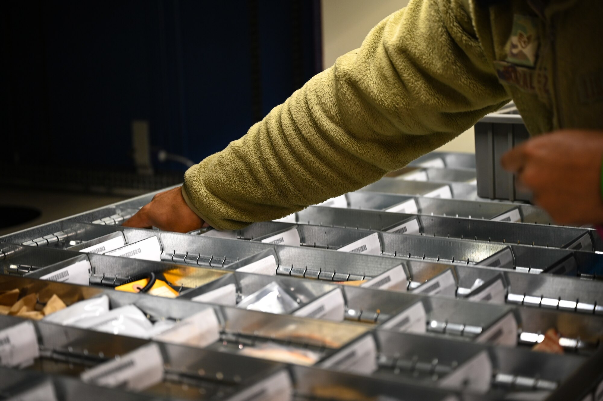 A military member puts their hand in a bin.