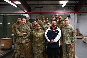 Group of military members and a civilian gather for a group photo.