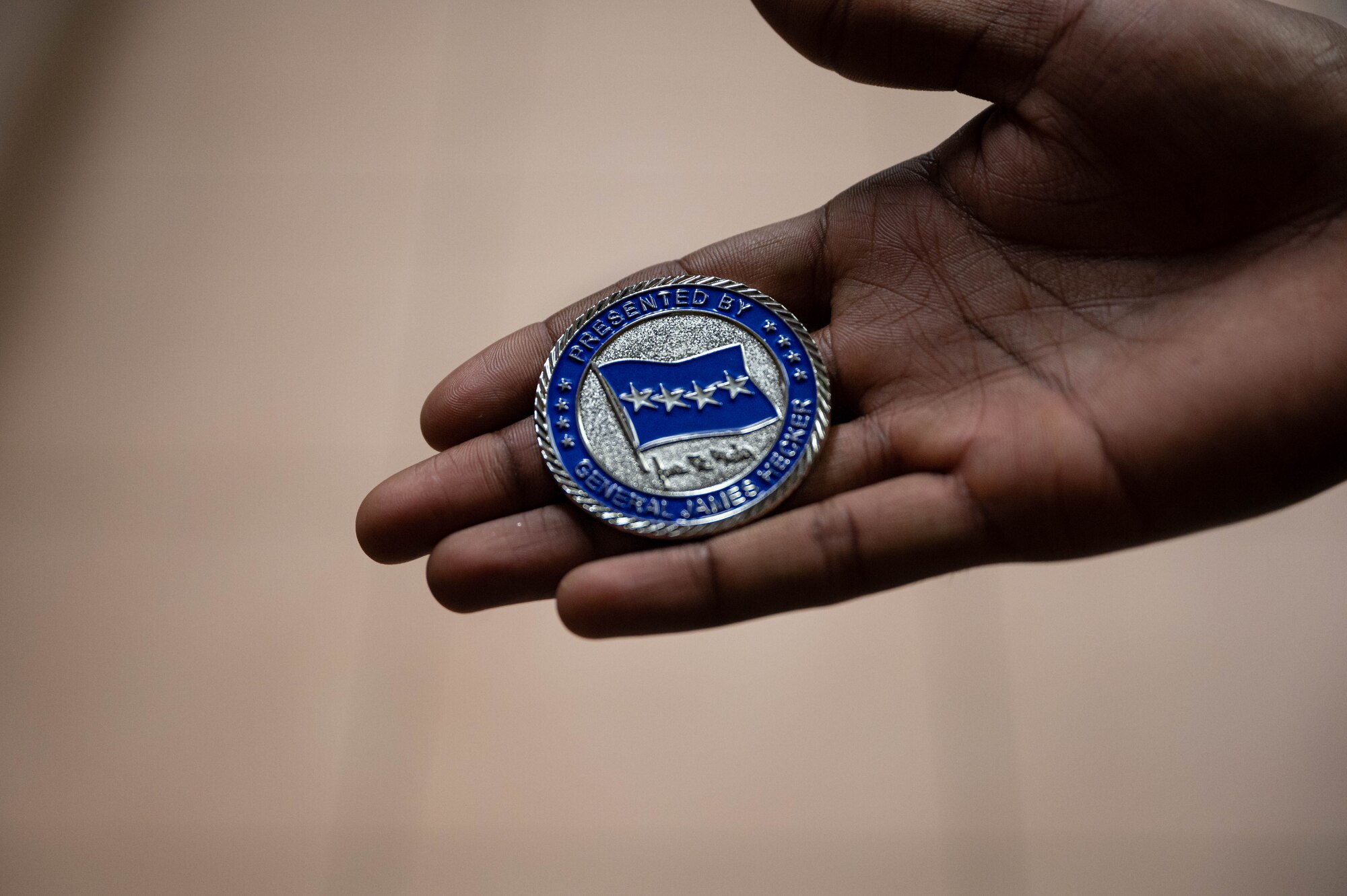 An Airman holds a coin.
