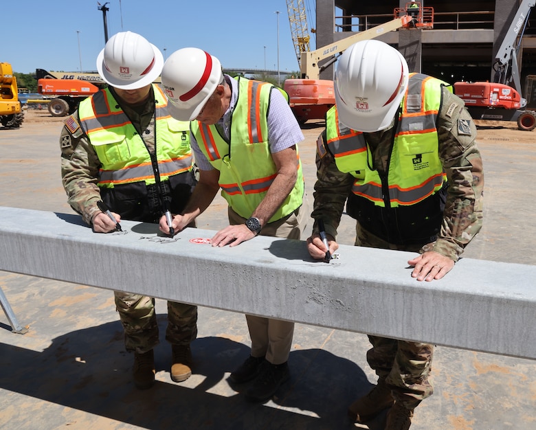 Three Men signing a building beam.
