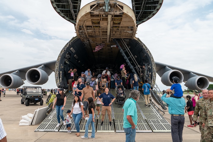 The Great Texas Airshow attendees walk out of the 433rd Airlift Wing’s C-5M Super Galaxy near the entrance of the airshow at Joint Base San Antonio-Randolph, Texas Apr. 7, 2024. In the center of the ramp stands Staff Sgt Jammie Lee Lueck, Air and Space Force recruiter, poses for a photo to commemorate the C-5 as her inspiration to join the Air Force.