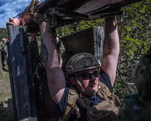 Hospital Corpsman 3rd Class Elisha Rogers lifts a simulated patient over his head through an obstacle course as part of the initial course implementation of En-route Care System (ERCS), March 14. ERCS is one of the Navy’s expeditionary medicine capabilities that provides a ready, rapidly deployable and combat effective medical forces to improve survivability across the full spectrum of care, regardless of environment. and revised provides uninterrupted care during patient movement from the point of injury (POI) through Role 4 care without clinically compromising the patients’ condition. The Navy Medicine Operational Training Command (NMOTC) is the Navy’s leader in operational medicine and trains specialty providers for aviation, surface, submarine, expeditionary, and special operations communities. (U.S. Navy photo by Mass Communication Specialist 1st Class Russell Lindsey SW/AW)