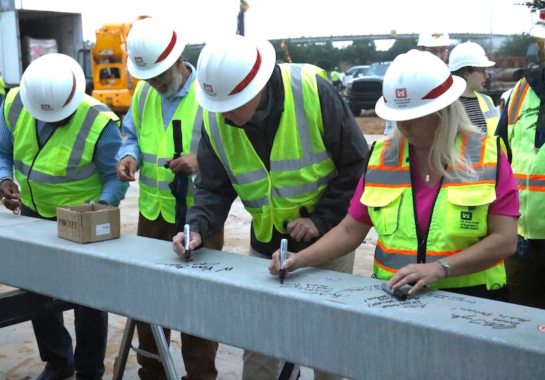 Four people signing build beam