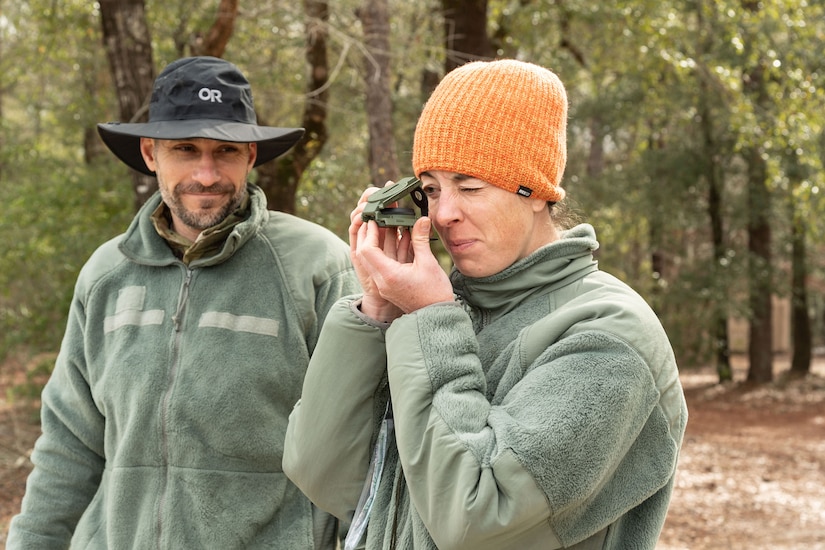 A person looks through a piece of wilderness survival equipment as a another person watches.