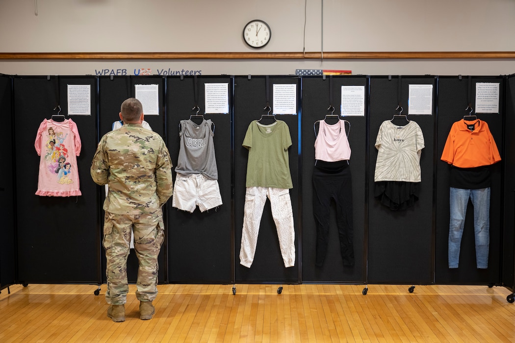 A man in a military uniform reads stories of sexual assault survivor on display