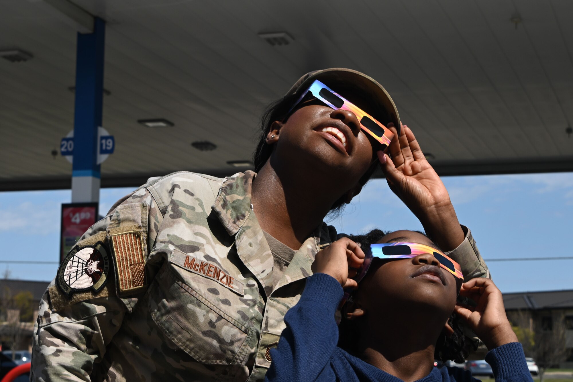 Woman in uniform and child look up toward sky.