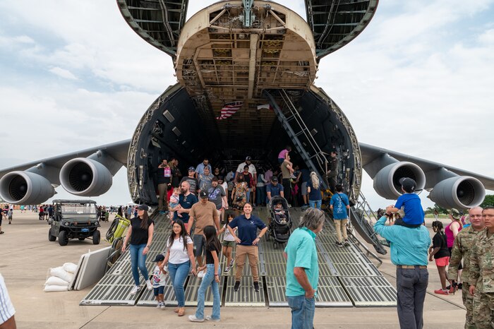 The Great Texas Airshow attendees walk out of the 433rd Airlift Wing’s C-5M Super Galaxy near the entrance of the airshow at Joint Base San Antonio-Randolph, Texas Apr. 7, 2024. In the center of the ramp stands Staff Sgt Jammie Lee Lueck, Air and Space Force recruiter, poses for a photo to commemorate the C-5 as her inspiration to join the Air Force.