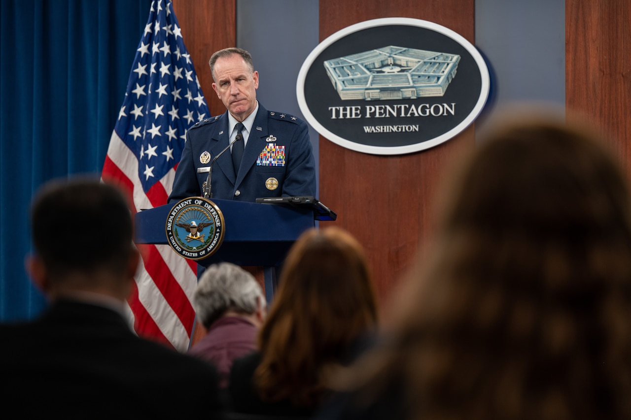 A man in a military uniform stands behind a lectern.