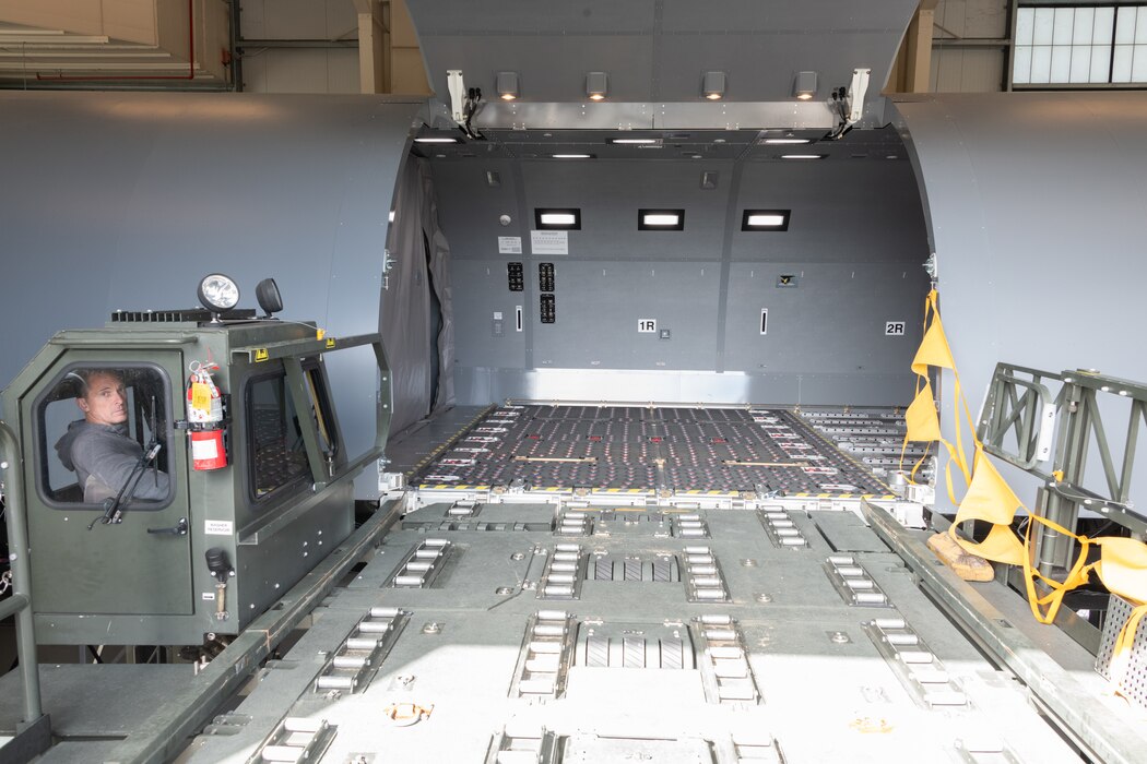 A cargo loading vehicle drives into position at the KC-46 fuselage trainer.