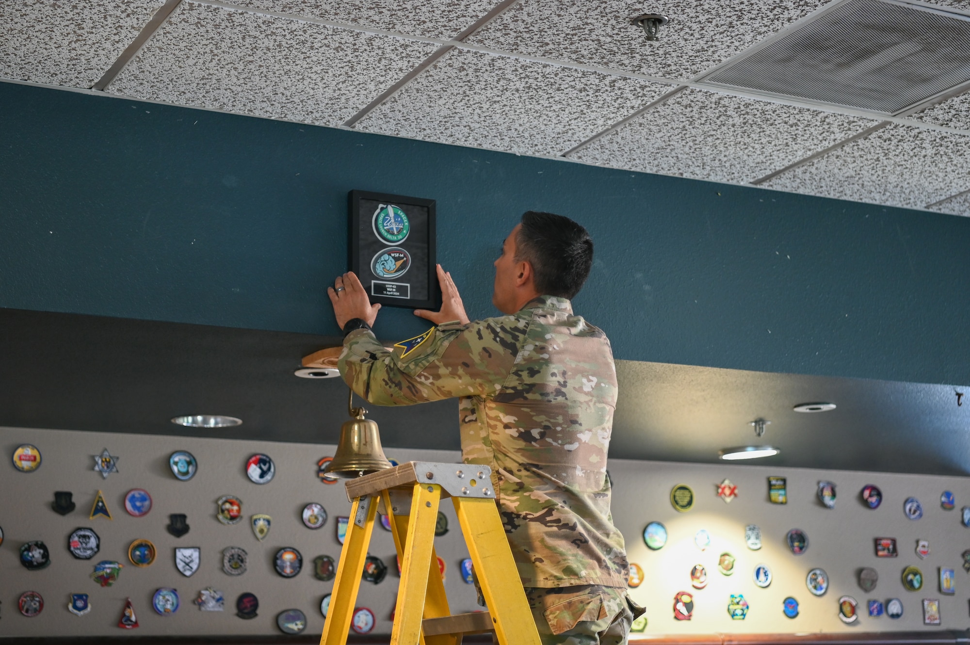 A 2nd Range Operations commander, places the first USSF patch of 2024 on the wall during a patching ceremony for USSF-62 at Vandenberg Space Force Base.