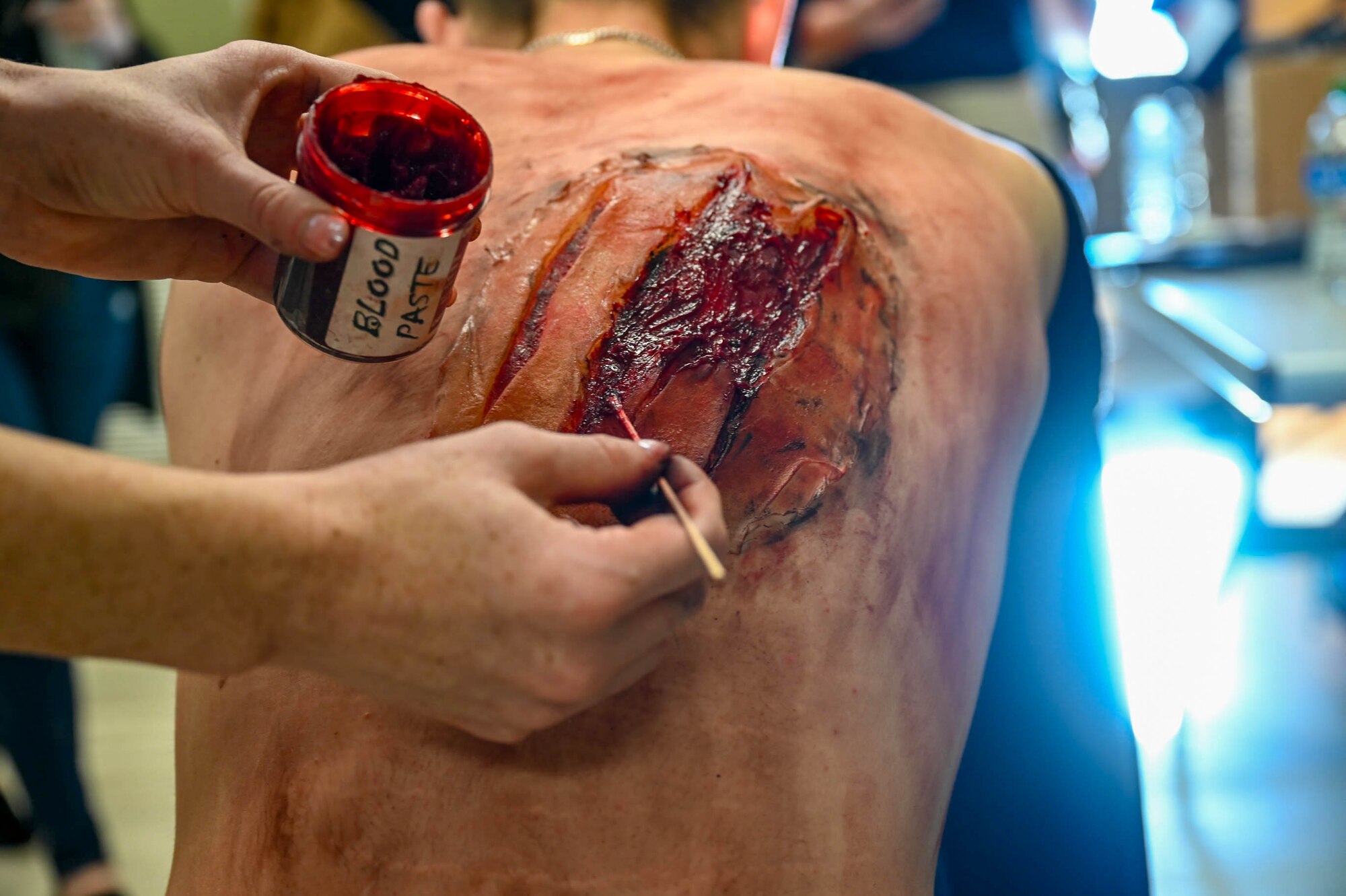 A student from the 81st Training Group receives an artificial wound from a moulage artist at a disaster exercise at Gulfport-Biloxi International Airport, Gulfport, Mississippi, March 28, 2024.