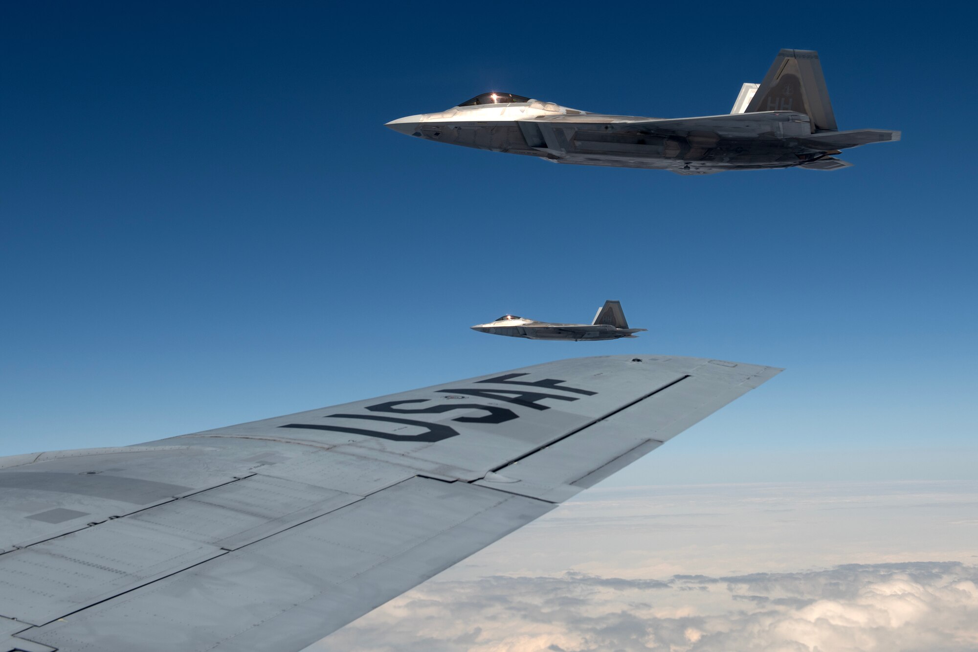 F-22A Raptors assigned to the 19th Fighter Squadron, Joint Base Pearl Harbor–Hickam, Hawaii, fly alongside a 909th Air Refueling Squadron KC-135 Stratotanker during a large force exercise over the Pacific Ocean, April 10, 2024. The rotational presence of advanced fighter aircraft in the keystone of the pacific enables the 18th Wing to practice large-scale exercises to ensure a free and open Indo-Pacific. (U.S. Air Force photo by Staff Sgt. Jessi Roth)