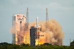 A rocket launches into the sky from a tower with the United States flag.