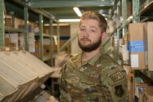 U.S. Air Force Senior Airman Travis Spong, 35th Force Support Squadron registered mail clerk, poses in front of rows of mail at Misawa Air Base, Japan, March 28, 2024.