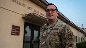 Staff Sgt. Jordan Whitworth stands in front of the weather and base operations office.