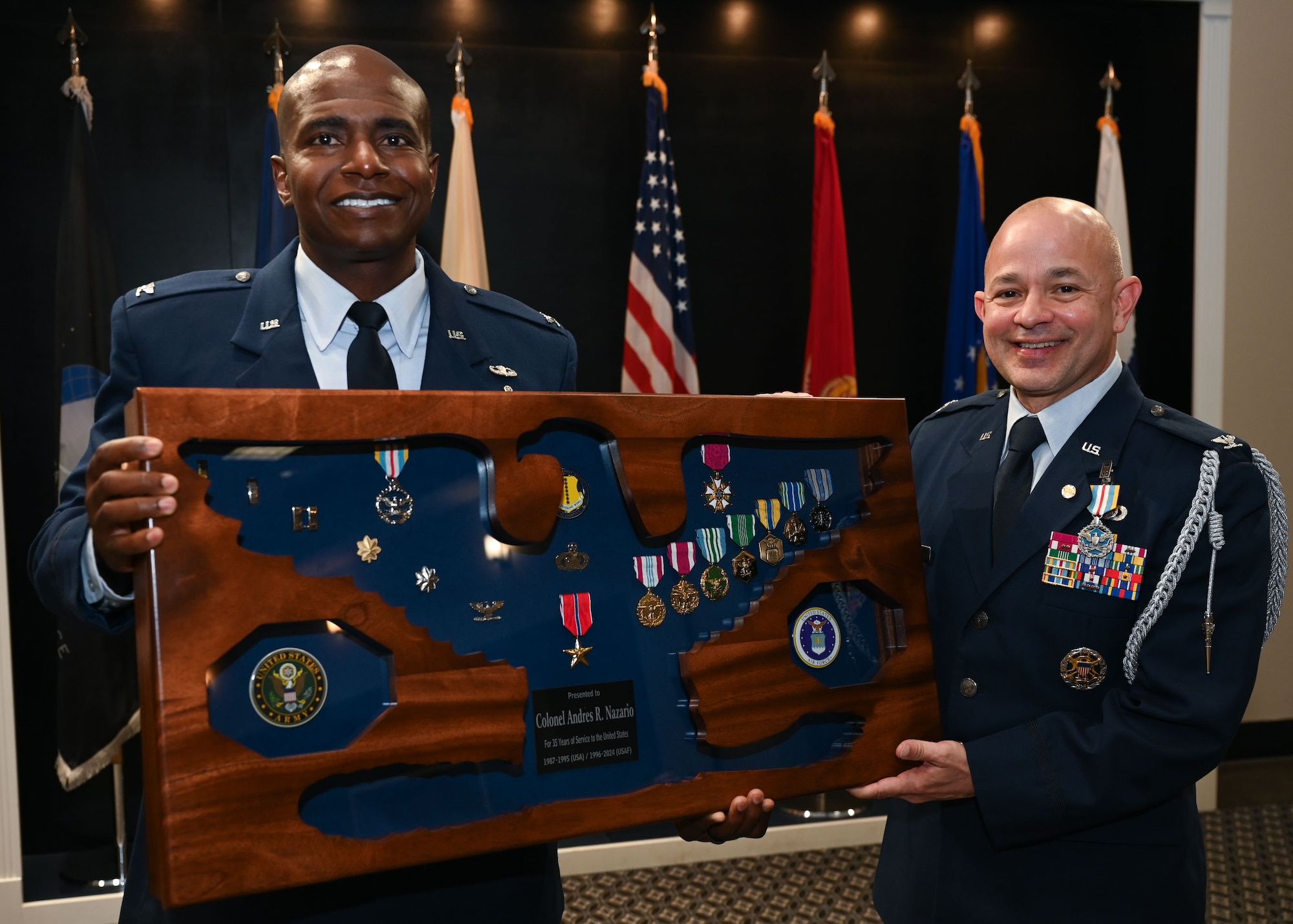 U.S. Air Force Col. James Finlayson, Air Force Technical Applications Center commander, presents a shadowbox to Col. Andres Nazario, United States Air Attache to Mexico, during Nazario’s retirement ceremony at the Powell Event Center, Goodfellow Air Force Base, Texas, April 2, 2024. Finlayson served as deputy commander with Nazario during his time as wing commander at Goodfellow. (U.S. Air Force photo by Airman 1st Class Evelyn D’Errico)
