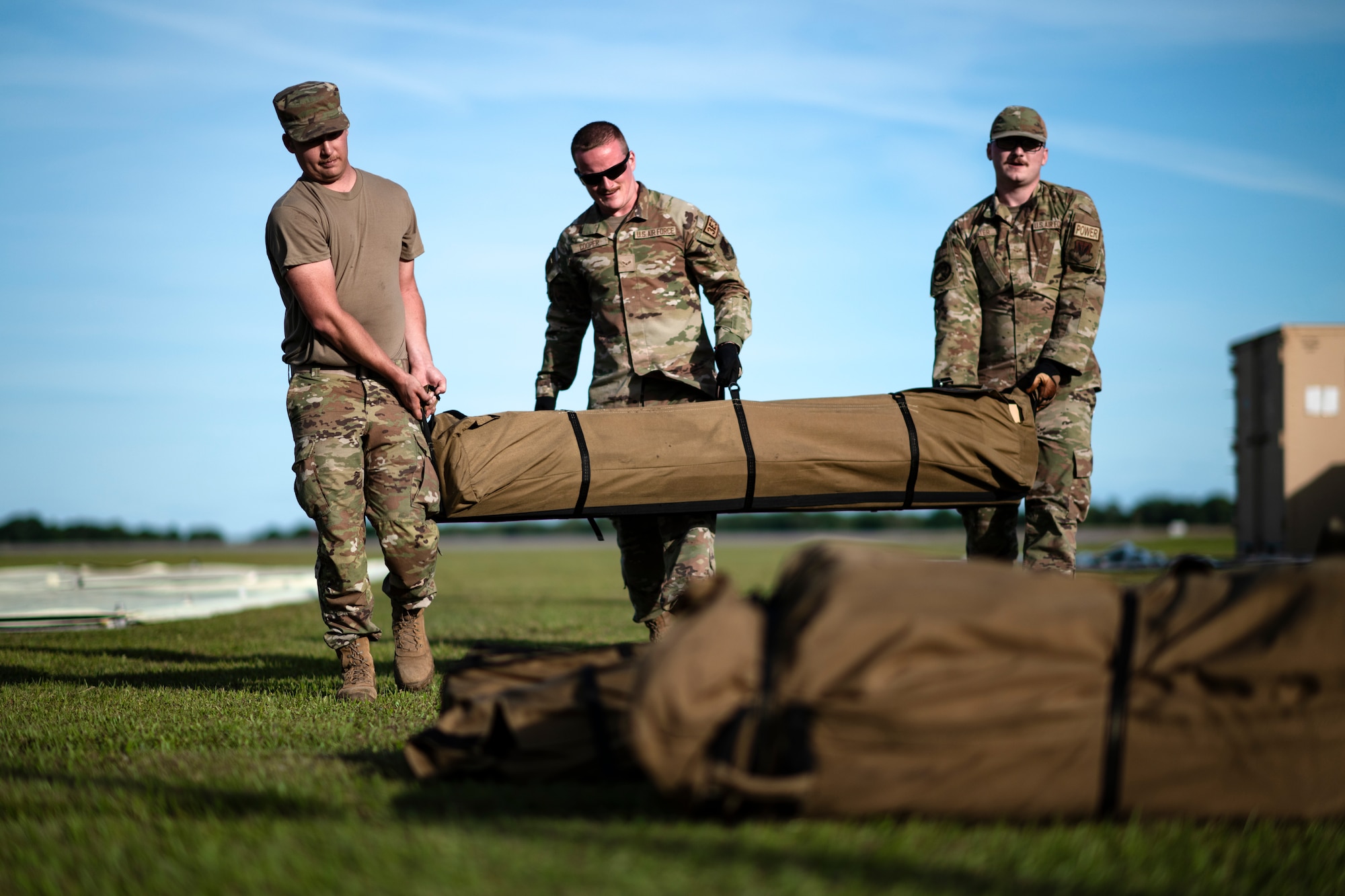 U.S. Air Force Senior Airman Jacob Kangas, 23rd Civil Engineer Squadron structural journeyman; Airman 1st Class Nathaniel Cooper, 23rd CES structural apprentice; and Airman 1st Class Mark Riester, 23rd CES power production apprentice, carry tent equipment at Avon Park Air Force Range, Florida, April 8, 2024. The Airmen established shelters to support food provisions, maintenance operations, and communications for the 23rd Air Base Squadron’s forward operating site. Built upon Air Combat Command's directive to assert air power in contested environments, exercise Ready Tiger 24-1 aims to test and enhance the 23rd Wing’s proficiency in executing Lead Wing and expeditionary air base concepts through Agile Combat Employment and command and control operations. (U.S. Air Force photo by Tech. Sgt. Devin Boyer)