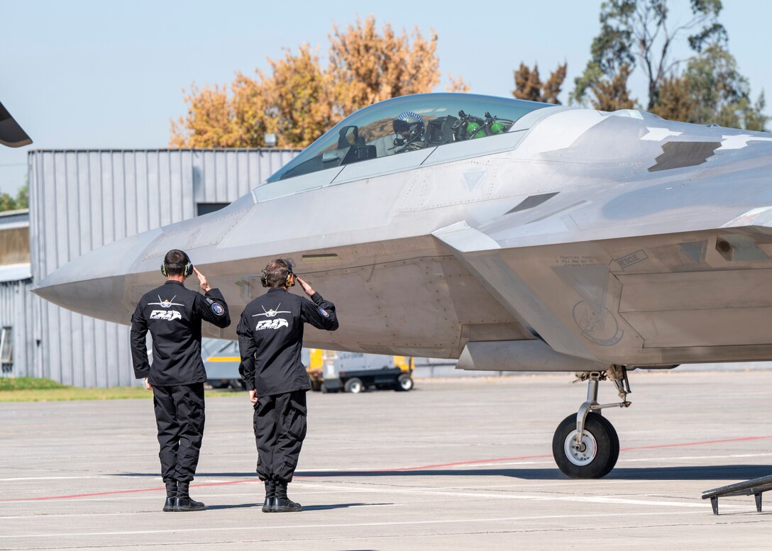 U.S. Airmen from the F-22 Raptor Demonstration Team salute their pilot and commander.