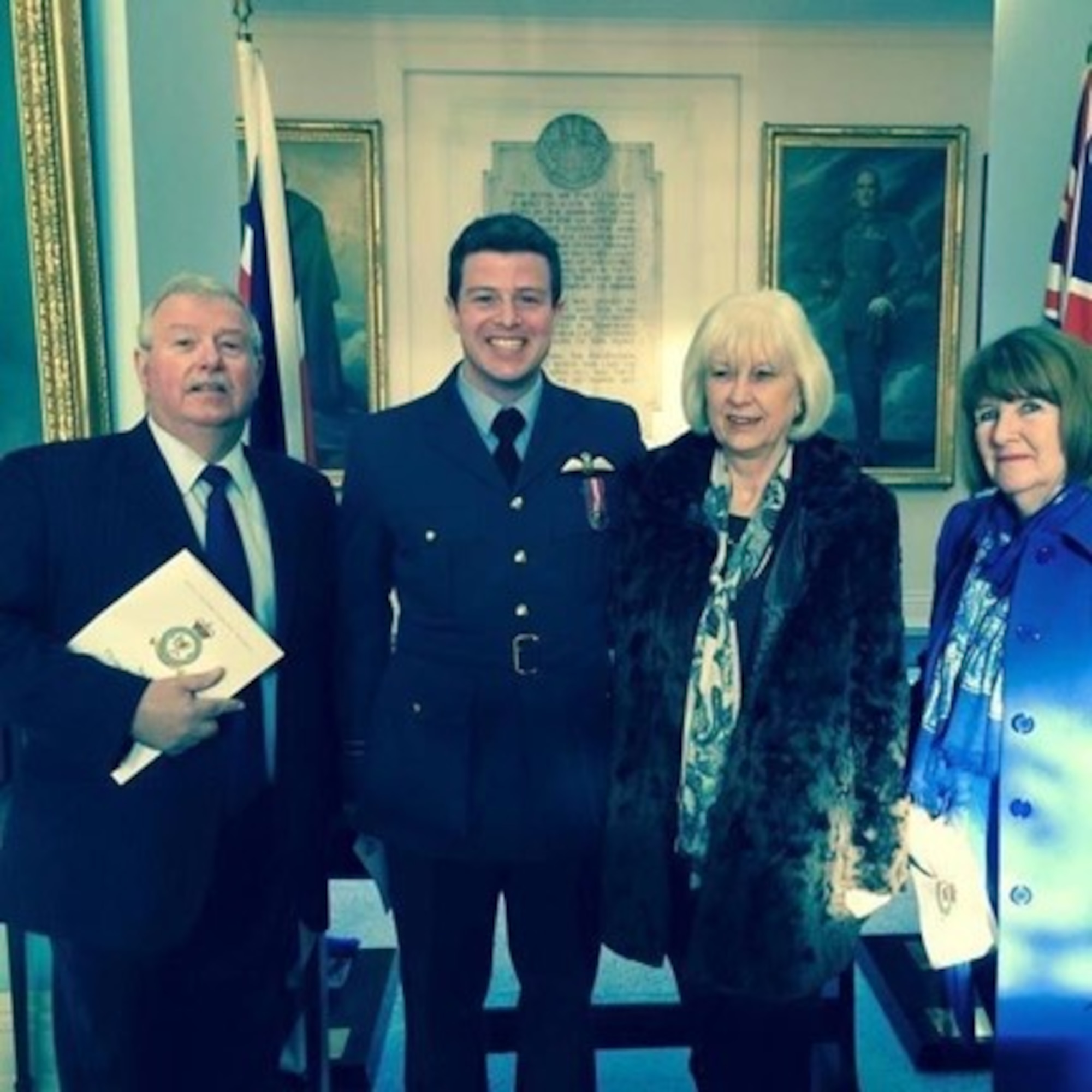 A man in military uniform poses for a photo with two women and a man.