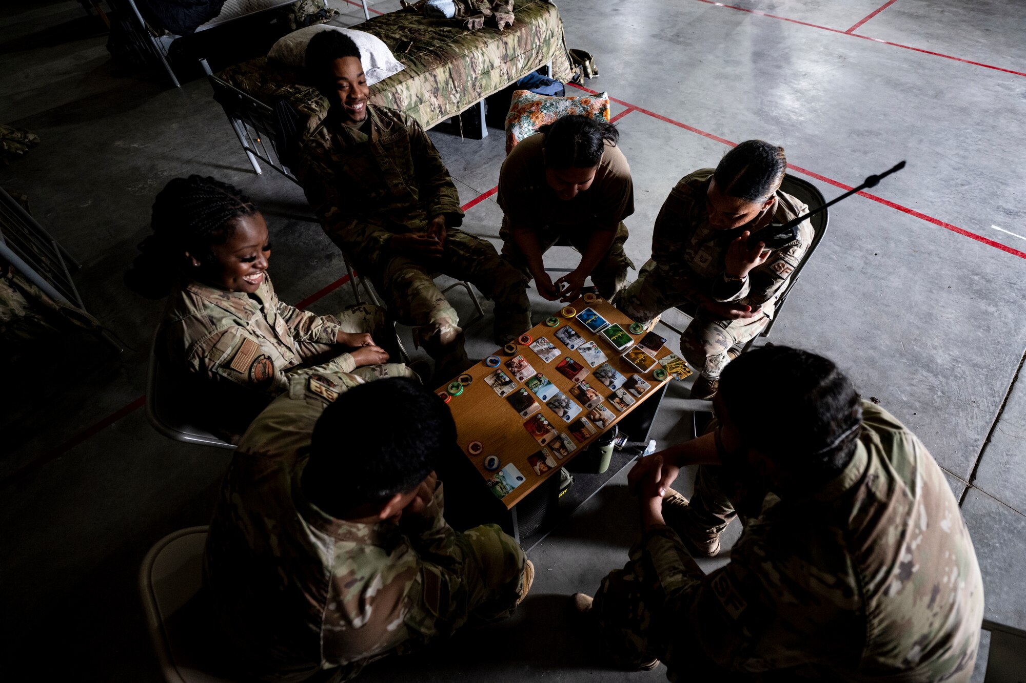 U.S. Air Force Airmen assigned to the 23rd Security Forces Squadron play a card game at Avon Park Air Force Range, Florida, April 9, 2024. Airmen established a living area inside a hangar for exercise Ready Tiger 24-1 and participated in morale-boosting activities, which is critical to maintaining mental readiness for mission success. During Ready Tiger 24-1, exercise inspectors will assess the 23rd Wing's proficiency in employing decentralized command and control to fulfill air tasking orders across geographically dispersed areas amid communication challenges, integrating Agile Combat Employment principles such as integrated combat turns, forward aerial refueling points, multi-capable Airmen, and combat search and rescue capabilities. (U.S. Air Force photo by Tech. Sgt. Devin Boyer)
