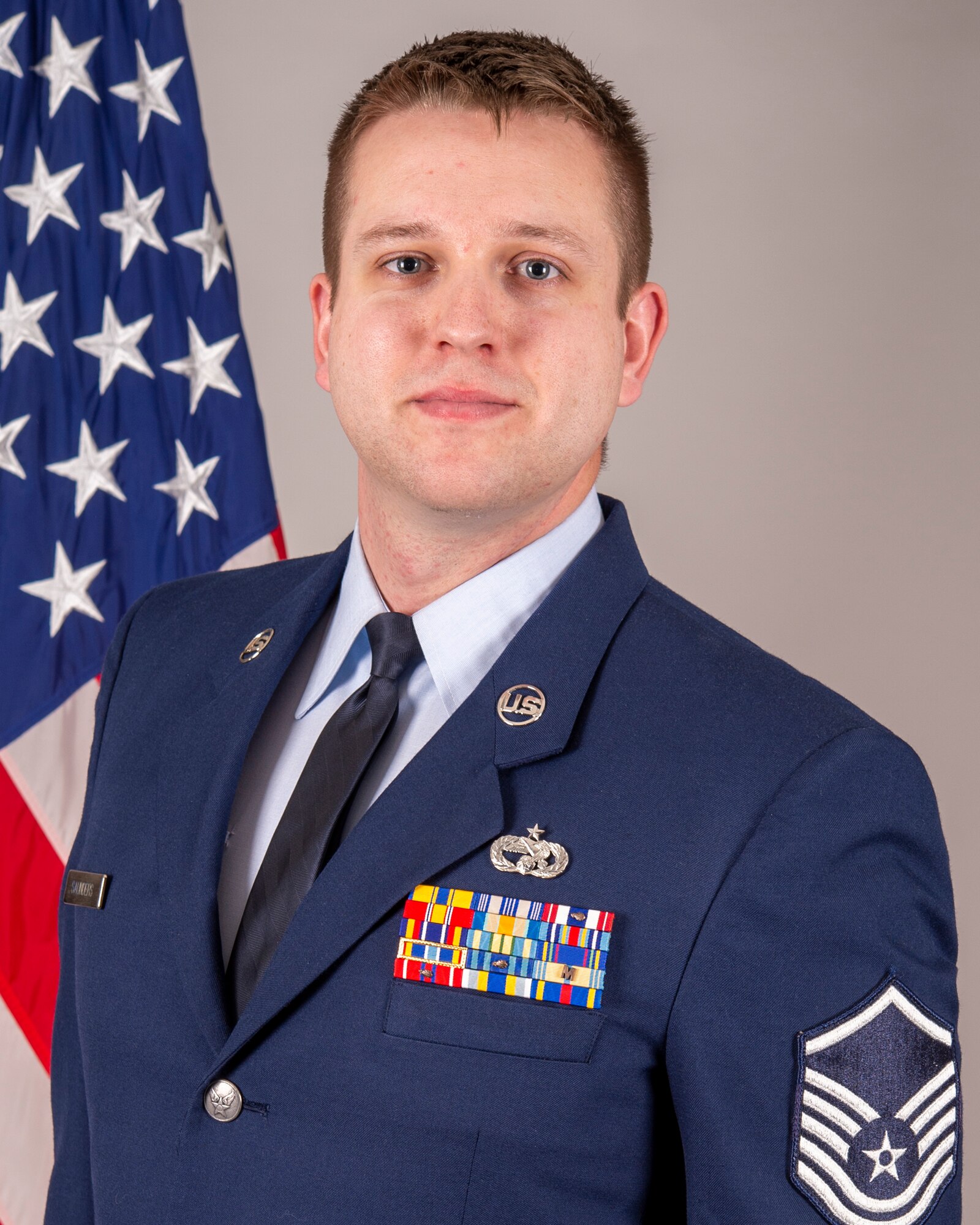 A man in a U.S. Air Force dress uniform with the rank of Technical Sergeant on his sleeve poses for a photo.