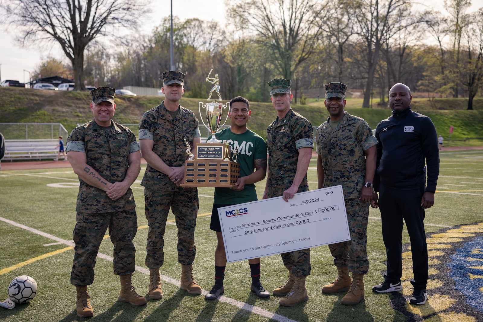 U.S. Marines pose for a group photo during the opening ceremony of the 2024 Commander’s Cup on Marine Corps Base Quantico, Virginia, April 9. 2024. Commands aboard the base competed in five different sports, to include golf, softball, football, basketball, and bowling. The 2023 winners, Officer Candidates School, were recognized at this year’s ceremony, where they earned a 1,000 dollar check and a t trophy from the base commander. (U.S. Marine Corps photo by Lance Cpl. Joaquin Dela Torre)