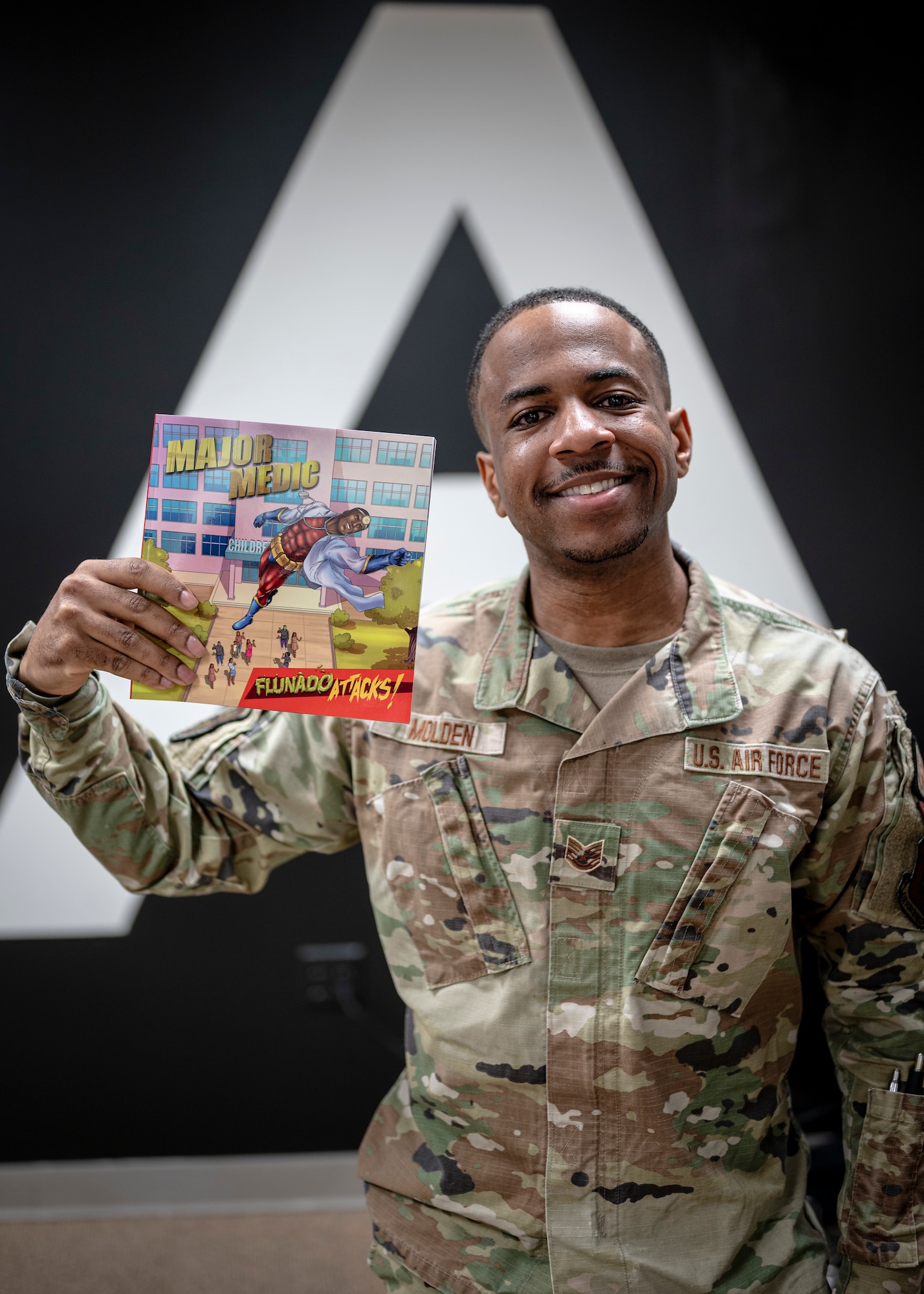 Man in military uniform holds up comic book he created