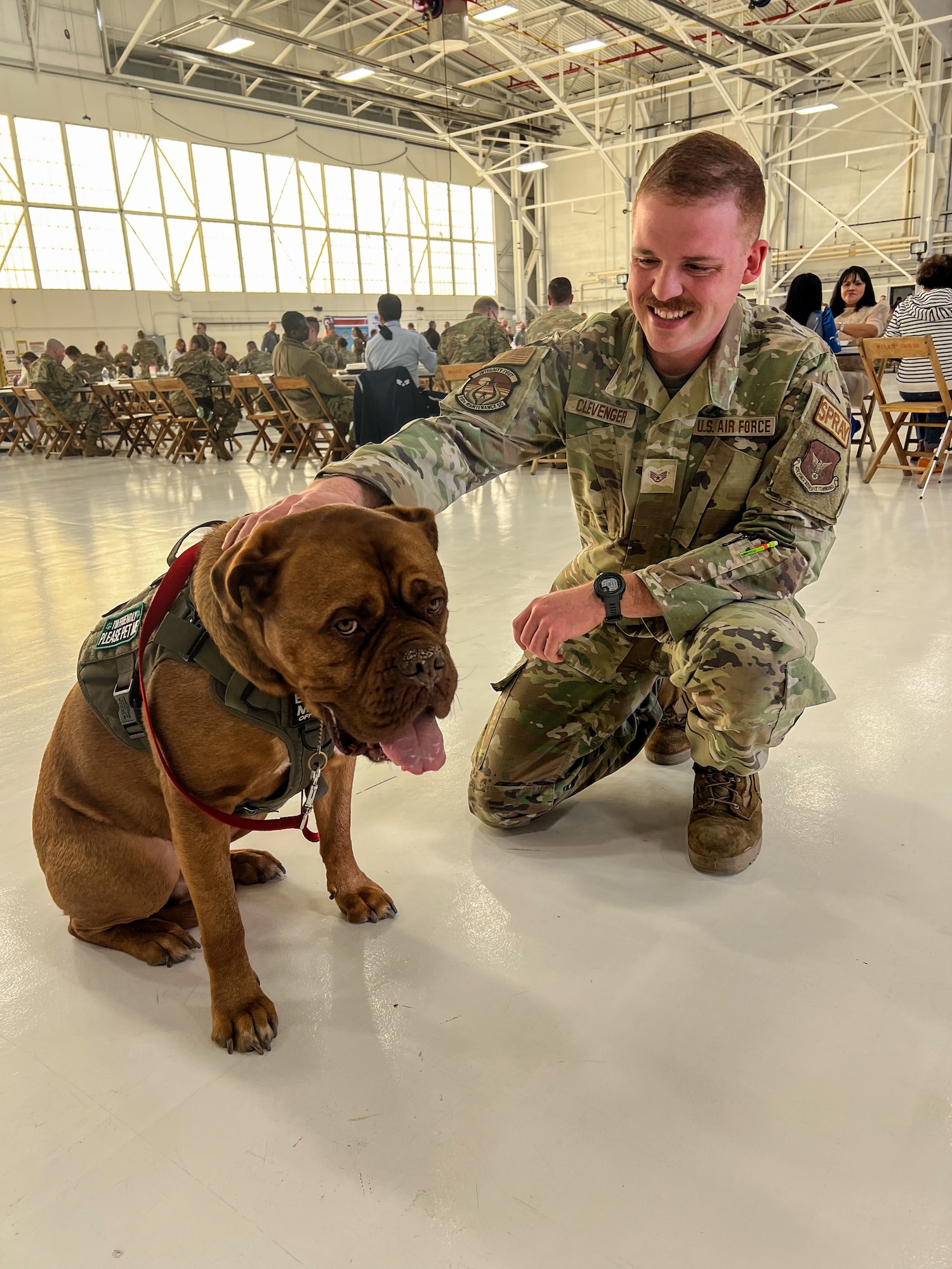 Staff Sgt. Jacob Clevenger, an aircraft maintenance helper assigned to the 910th Maintenance Squadron, and Atticus, University Hospital service dog, pose for a photo during the 910th Airlift Wing Career and Diversity Day, April 6, 2024, at Youngstown Air Reserve Station, Ohio.