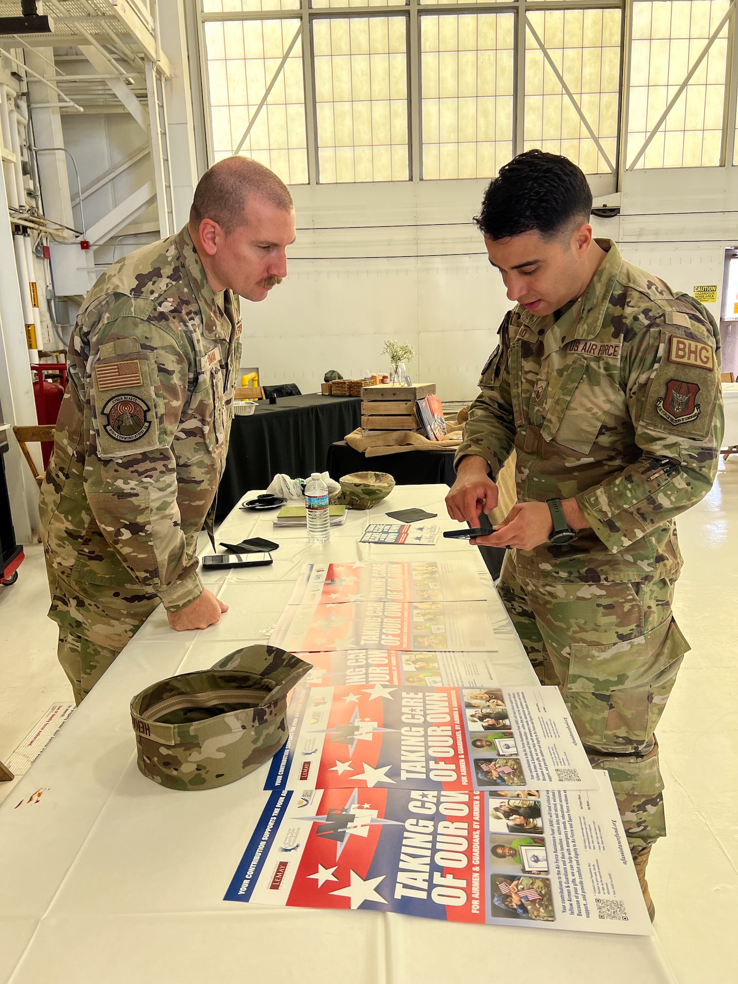 Senior Master Sgt. Jared Shuman, 910th Communications Squadron superintendent, and Master Sgt. Felipe Henao, 910th Airlift Wing first sergeant, discuss how to donate money to the Air Force Assistance Fund during the 910th AW Career and Diversity Day, April 6, 2024, at Youngstown Air Reserve Station, Ohio.